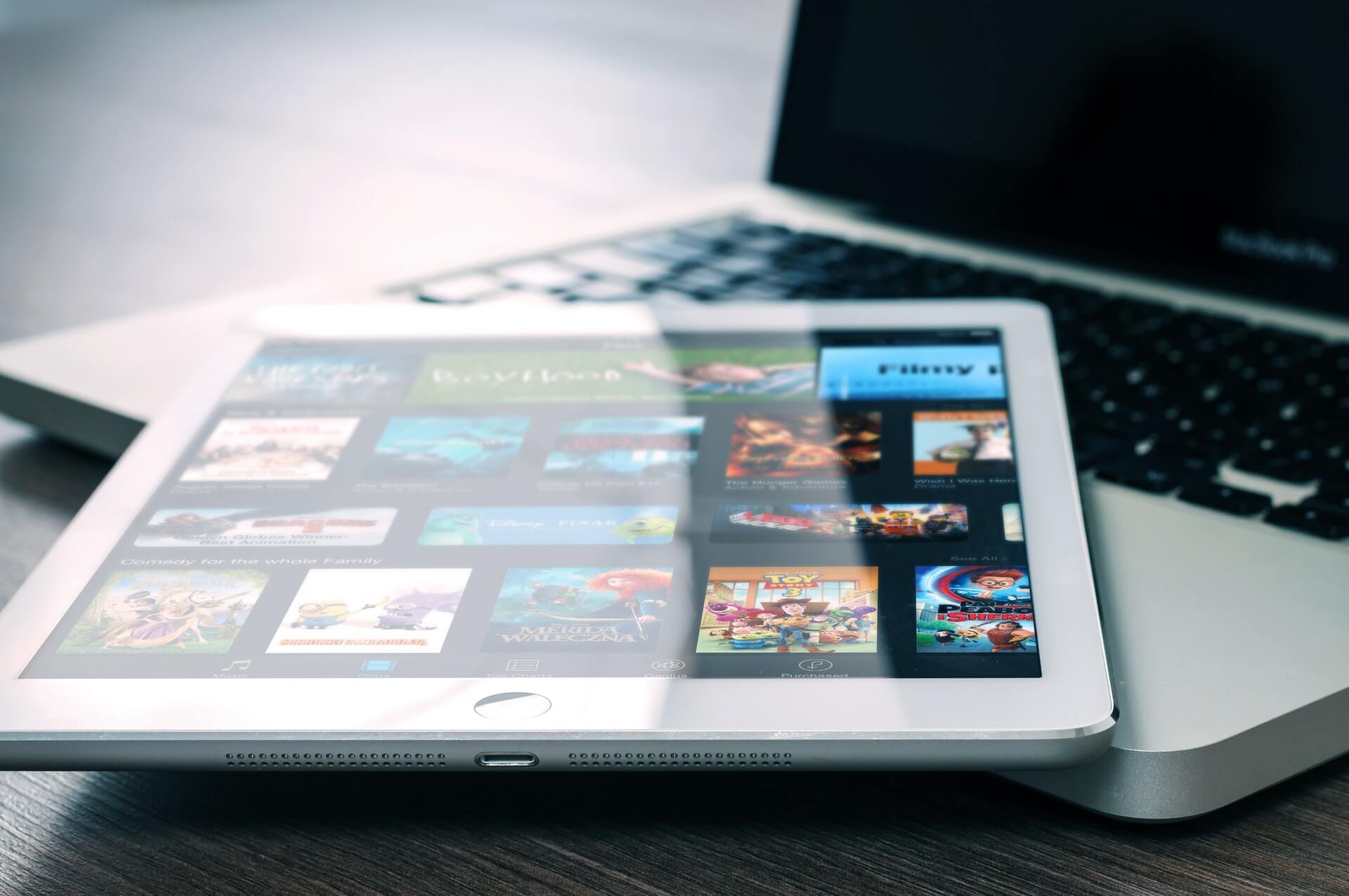 business-app A laptop placed on a wooden table with an iPad positioned on top of the laptop keyboard.