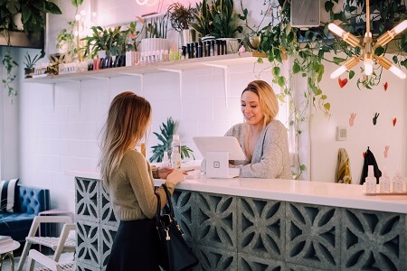 How To Get More Customers During The Holidays A customer talking to a woman on the front desk inside a beauty salon during holiday.