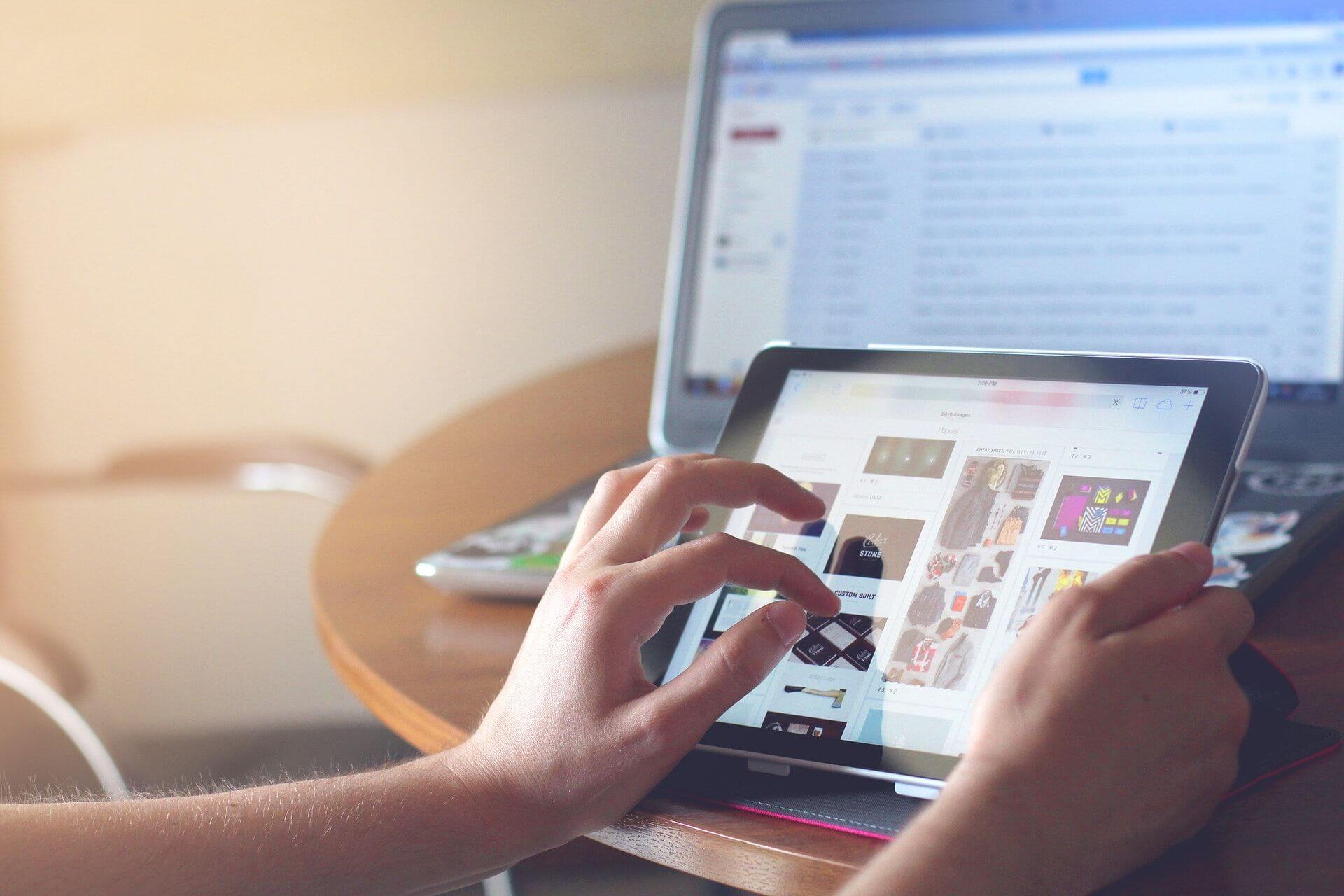 Is An E-commerce Business Really For You Person using a tablet with a laptop beside it on top of a table.
